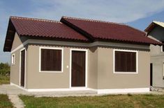 a small house with brown shutters on the roof and two windows in the front