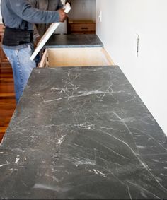 a man standing in a kitchen next to a counter top with a large knife sticking out of it