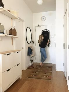 a woman standing in front of a white door with a black backpack on her back