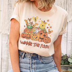 a woman wearing a winnie the pooh t - shirt with pumpkins on it