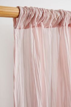 a pink curtain hanging from a wooden rod