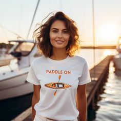 "Dive into adventure with our \"Paddle On\" t-shirt! This shirt is more than just fabric - it's an invitation to explore, to glide through life with a spirit of boundless curiosity. With a kayak design that captures the essence of motion on water, it's a reminder to keep pushing forward, embracing the currents of life. Wear it as a badge of your unstoppable journey, and let the waves of inspiration carry you. Let's \"Paddle On\" together! The unisex soft-style t-shirt puts a new spin on casual c Casual Short Sleeve T-shirt For Water Sports, Summer Water Sports Short Sleeve T-shirt, Short Sleeve Graphic Print Tops For Water Sports, Casual Short Sleeve Tops For Water Sports, Graphic Print Crew Neck Top For Water Sports, Crew Neck Top With Graphic Print For Water Sports, Casual Graphic Print T-shirt For Water Sports, Casual Crew Neck T-shirt For Water Sports, White Short Sleeve T-shirt For Outdoor Activities