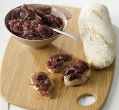 a wooden cutting board topped with food next to a loaf of bread