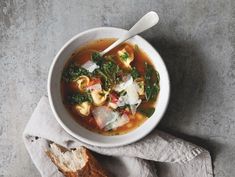 a white bowl filled with soup next to a piece of bread on top of a napkin