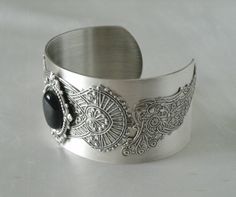 This beautiful silver plated cuff bracelet has a black onyx stone set on silver plated embellishments and silver plated gothic wings on the sides. Adjustable. Bohemian Cuff Jewelry For Formal Occasions, Metal Bangle With Jewels, Black Metal Cuff Bracelet As Gift, Black Metal Cuff Bracelet For Gift, Elegant Adjustable Cabochon Jewelry, Elegant Adjustable Filigree Jewelry, Ornate Metal Bracelet Jewelry, Elegant Adjustable Filigree Cuff Bracelet, Formal Cabochon Bracelet Jewelry