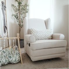 a white chair sitting next to a tree in a living room