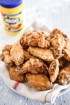 fried chicken on a white plate next to a jar of condiments and a napkin