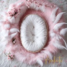 a white cushion with pink feathers on it and a flower arrangement in the middle, surrounded by flowers