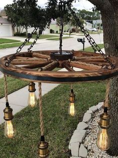 a light fixture hanging from the side of a tree in front of a sidewalk and grass area