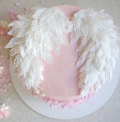 a cake with white feathers on top of it and pink frosting around the edges