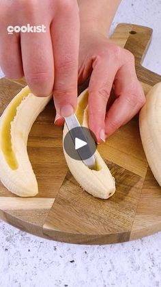 a person cutting bananas with a knife on a wooden board