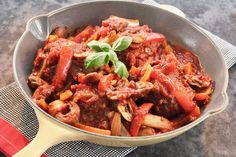 a pot filled with meat and vegetables on top of a table next to a red napkin