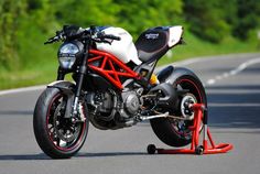 a red and white motorcycle parked on the side of a road