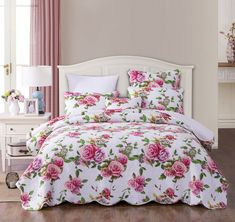 a white bed with pink roses on it in a room next to a dresser and window