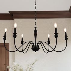 a chandelier with five lights hanging from the ceiling in a dining room area