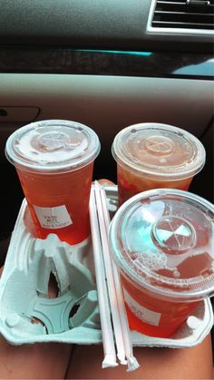 three plastic cups with drinks in them sitting on a tray