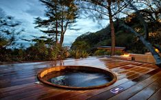 a hot tub sitting on top of a wooden deck next to a fire pit and trees