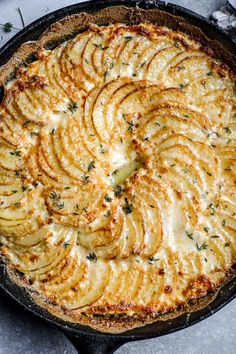 a baked dish in a cast iron skillet topped with potatoes and herbs, ready to be eaten