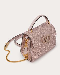 Mini Valentino Garavani VSLING handbag entirely covered in rhinestone with VLogo Signature closure. - The bag can be worn crossbody thanks to its extendable shoulder strap, and handheld thanks to its handle. - Hardware with an antique-brass finish - Magnetic closure with logo covered in Swarovski® crystals - Leather shoulder strap with adjustable chain - Protective feet - Nappa lining. Interior: flat open pocket - Drop Length: min 45 cm - max 59 cm - Sizes: W19xH13xD9 cm - Made in Italy High-end Pink Shoulder Bag For Evening, Luxury Shoulder Bag For Events, Luxury Top Handle Shoulder Bag For Events, Designer Pink Embellished Bags, Luxury Clutch Shoulder Bag With Rhinestones, Luxury Rhinestone Clutch Shoulder Bag, Luxury Pink Evening Bag With Rhinestones, Luxury Pink Rhinestone Evening Bag, Luxury Embellished Event Bags