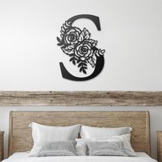 a bed with white sheets and pillows in front of a wooden headboard that has flowers on it