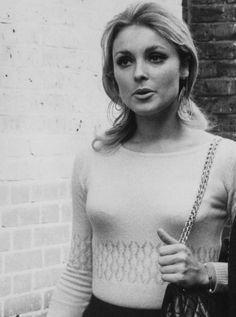 a black and white photo of a woman holding a handbag in her right hand