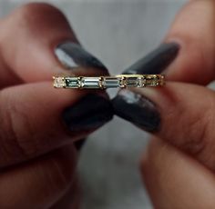 a woman's hands holding a gold ring with three baguettes