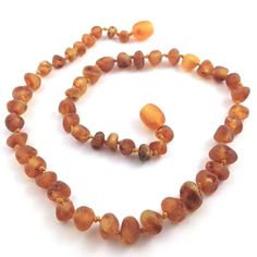 a necklace made out of glass beads on a white surface with an orange bead