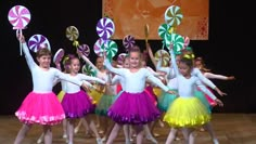 the children are dressed in colorful skirts and holding lollipops