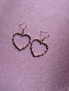 Let your love shine through with new hearts on hearts earrings from Cosmic Created Magic! Your heart is on full display with these romantic statement earrings! Dangling from hook gold earrings is a large gold heart outline. There are 12 tiny pink hearts around the edges of the gold heart with dots in between for texture and dimension. These big hearts are lightweight for comfortable wear. Give your sweetheart a gift she'll love from Cosmic Created Magic! Elegant Pink Heart Metal Earrings, Feminine Gold Heart Earrings For Valentine's Day, Cute Rose Gold Earrings For Valentine's Day, Rose Gold Metal Heart Earrings For Valentine's Day, Dainty Heart-shaped Earrings For Parties, Valentine's Day Rose Gold Heart Earrings For Party, Metal Heart Earrings With Heart Beads, Feminine Dangle Heart Earrings For Valentine's Day, Valentine's Day Heart Metal Earrings