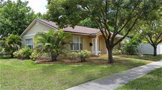 a house with lots of trees in front of it and grass on the lawn behind it