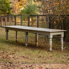 an old wooden bench sitting in the middle of a field with leaves on the ground