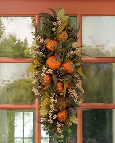 a wreath with oranges and berries hanging from the side of a window sill