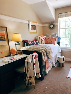 a bed room with a neatly made bed next to a window and a desk in front of it