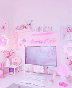 a white desk topped with a computer monitor next to a pink neon sign and flowers