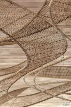 an artistic sculpture made out of wicker hanging from the ceiling in a room with wood flooring