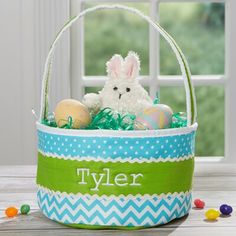 a blue and green basket with an easter bunny sitting in it next to some candy