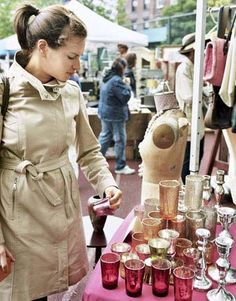 a woman standing next to a table filled with cups and glasses on top of it