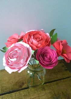 three paper flowers in a vase on a table