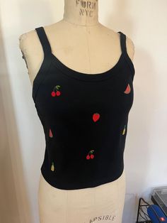 Cute summery cropped tank top embroidered with small fruit motifs - watermelon, cherry, strawberry, and pineapple. Made from a super soft and stretchy cotton/poly blend. Color: black Size pictured: L (on size 4 dress form) Please note: there was a small tear in the tank top that I was mostly able to cover with the pineapple embroidery, but some stitches are still visible on the right - see detail photo. Fitted Fruit Print Summer Tops, Cute Summer Crop Tank Top, Summer Cute Crop Tank Top, Summer Sleeveless Top With Cherry Print, Casual Sleeveless Top With Strawberry Print, Cute Crop Top Tank Top For Summer, Sleeveless Top With Cherry Print For Summer, Fitted Sleeveless Top With Cherry Print, Sleeveless Cherry Print Top For Summer