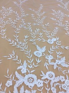 white flowers and leaves are embroidered onto the sheer fabric on this bed sheet that is made with lace