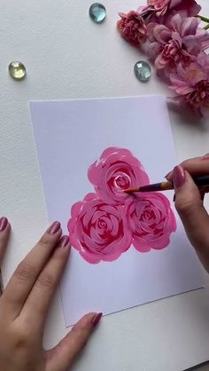 someone is painting flowers on a card with pink watercolors and acrylic paint