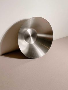 a metal object sitting on top of a white table next to a light brown wall