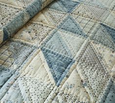 a blue and white patchwork quilt on top of a bed