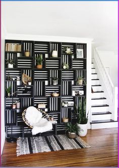 a living room with black and white striped walls, potted plants and a chair