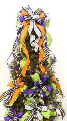 a decorated christmas tree with orange, green and purple ribbons on it's top