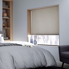 a bed sitting next to a window covered in gray sheets and pillows with a bookcase behind it