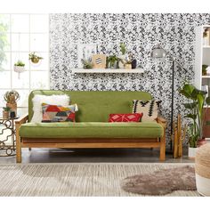 a green couch sitting in front of a wall with black and white designs on it