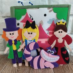 three felt dolls standing next to each other in front of a frame with a cartoon character on it