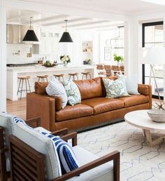 a living room filled with lots of furniture and white walls in front of an open floor plan