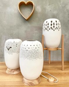 two white vases sitting on top of a wooden table next to a heart shaped object